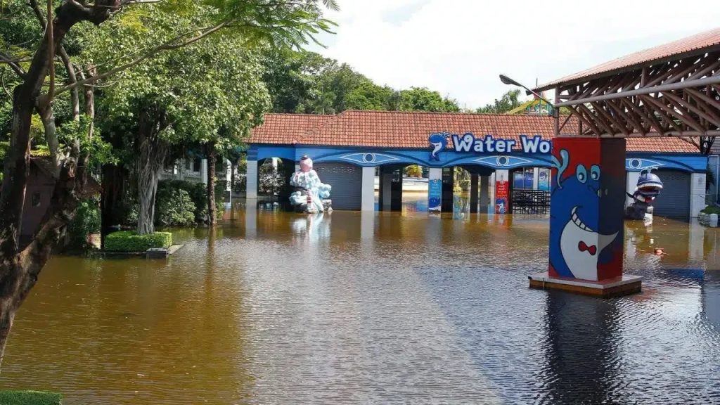 Den blå entrén till Water World med tecknade figurer, omgiven av brunt översvämningsvatten