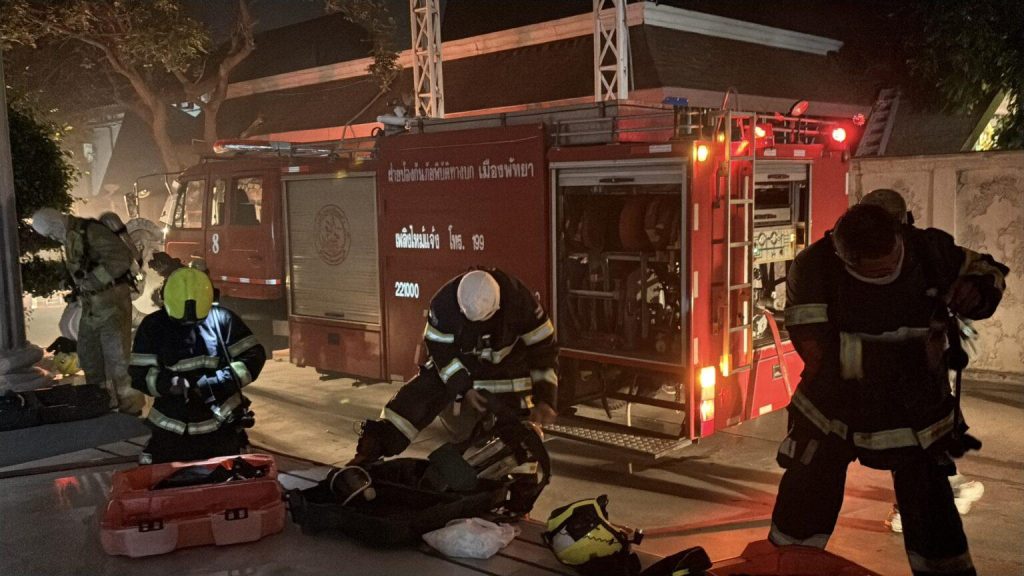 Brandman tar pa sig andningsskydd framfor brandbil i morkret