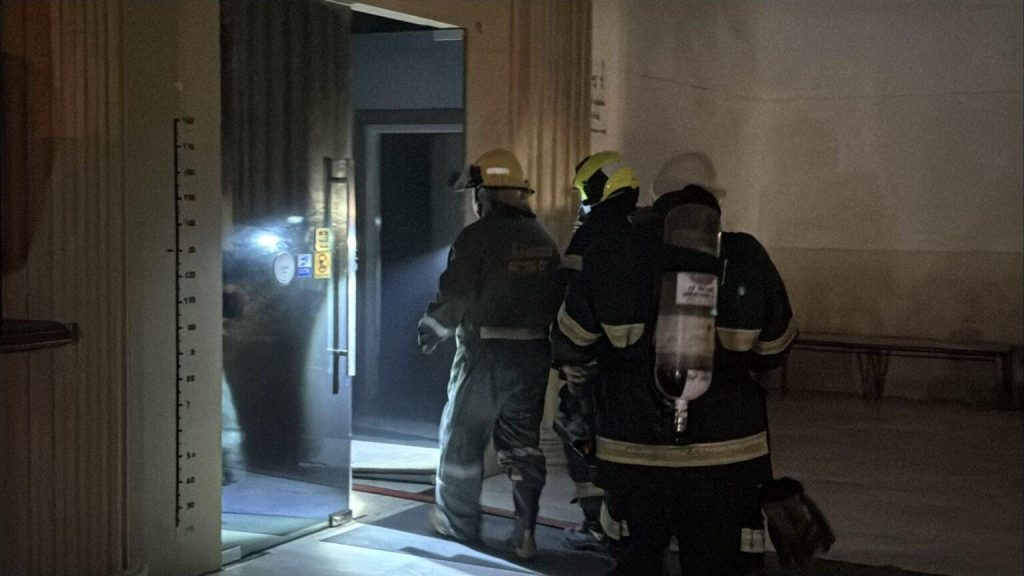 Tre brandman med andningsapparat pa vag in genom en dorr