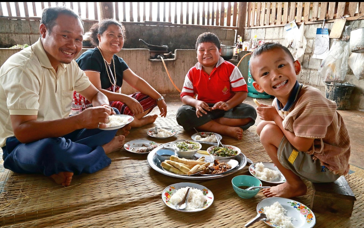 En thailändsk familj äter tillsammans på golvet.