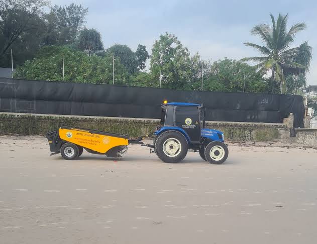 Traktor med strandsopmaskin pa sanden i Hua Hin