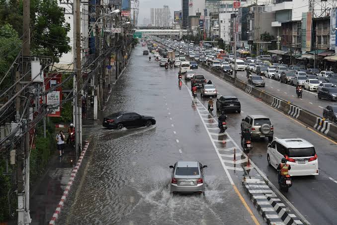 Trafik tar sig fram genom vatten pa en huvudgata i Bangkok